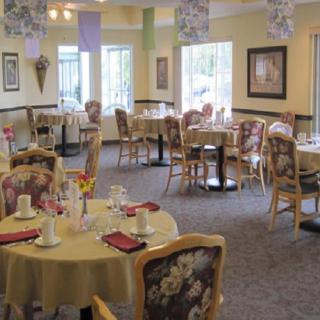 A cozy dining room with elegantly set tables and comfortable chairs, ready for guests.