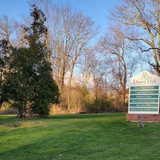 A peaceful park scene featuring trees and a sign, bathed in warm sunlight.