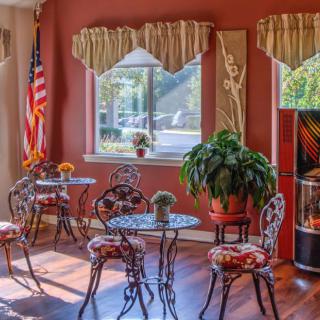 A cozy cafe interior with elegant tables and chairs, decorated with plants and natural light from the window.