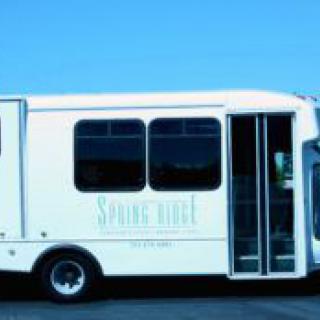 A white shuttle bus parked outdoors on a clear day.