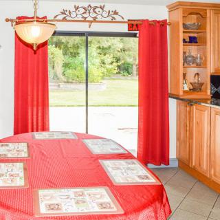 A cozy kitchen dining area with red curtains and wooden cabinets.
