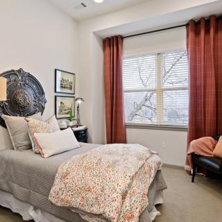 A cozy bedroom with elegant decor and a large window adorned with red curtains.