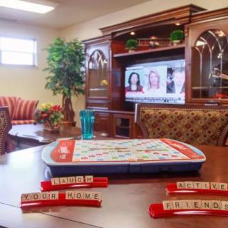 A cozy living room with a Scrabble game set up on the table and a television in the background.