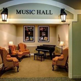 A cozy music hall with a piano, comfortable seating, and decorative artwork.