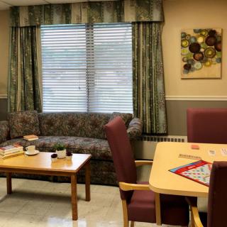 A cozy living room with a sofa, coffee table, and board game setup near a window with curtains.