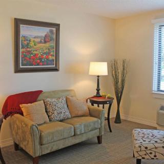 A cozy living room with a sofa, lamp, and a painting above the seating area.