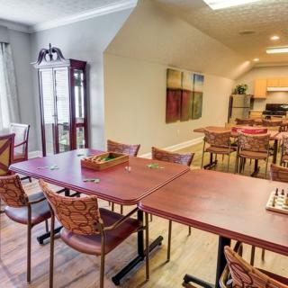A spacious dining room with tables and chairs, adjacent to a kitchen area.