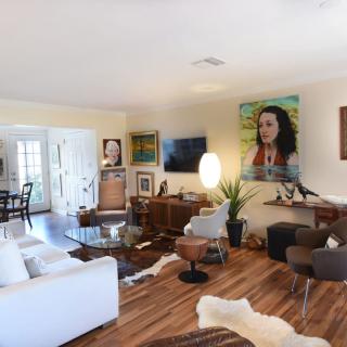 A modern living room featuring a mix of furniture, artwork, and wooden flooring.