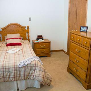 A cozy bedroom with a single bed, wooden furniture, and neutral decor.