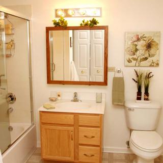 A clean and neatly organized bathroom with a vanity, mirror, shower, and toilet.