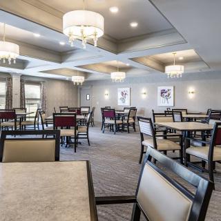 A modern dining room with elegant chandeliers and neatly arranged tables and chairs.