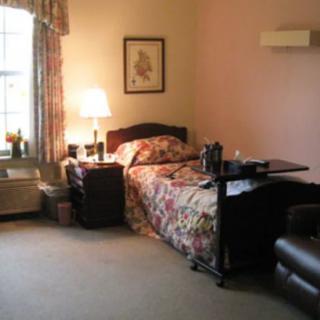 A cozy bedroom with a single bed, bedside lamp, and window with curtains.