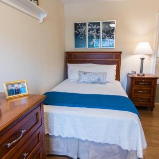 A cozy bedroom with a single bed, nightstand, and lamp, featuring blue accents.