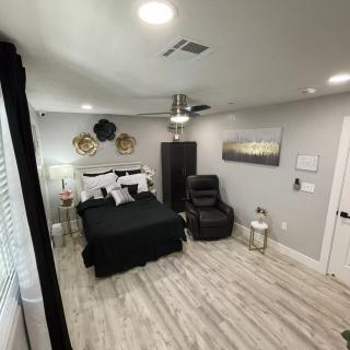A modern bedroom with black and white decor, featuring a bed, lounge chair, and wood flooring.