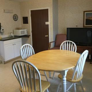 A cozy dining and kitchen area featuring a round table, four chairs, a microwave, and a television.