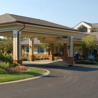 A spacious building entrance with a covered driveway and landscaped surroundings.