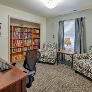 A cozy home office with a bookshelf and comfortable seating.