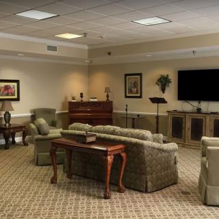 A cozy living room setup with sofas, chairs, and a large television, all arranged on a carpeted floor.