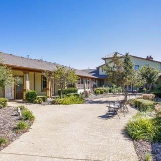 A suburban residential area with a walkway lined by well-maintained landscaping on a sunny day.