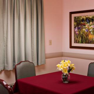 A cozy room with a red tablecloth, vase of flowers, and wall art.