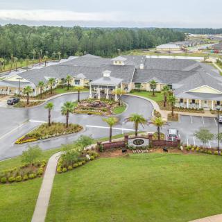 An aerial view of a large building surrounded by lush greenery and winding roads.