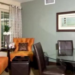A stylish living room featuring a mix of seating options, with a modern glass table and wall art accenting the space.
