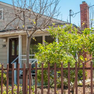 A charming house with a garden and wooden fence, featuring a porch and chimney.