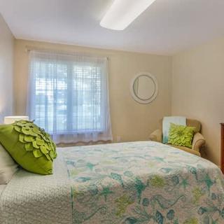 A cozy bedroom with a bed, decorative pillows, and a window.