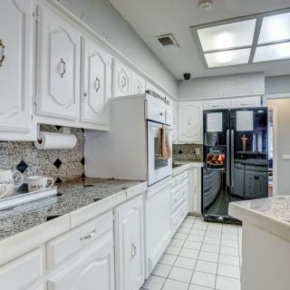 A modern kitchen with white cabinets, a refrigerator, and tiled flooring.