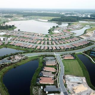 Aerial view of a suburban residential area with houses and surrounding water bodies.