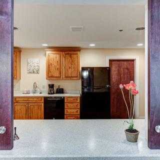 A modern kitchen with wooden cabinets and a visible countertop, featuring a potted plant and various appliances.
