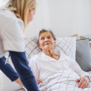 A caregiver attending to an elderly patient in bed.