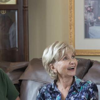 A group of people smiling while seated on a couch in a living room.