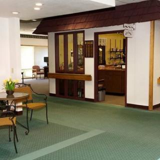 A cozy interior with a small seating area and carpet flooring, adjacent to a restaurant setup.
