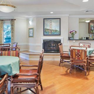 A cozy dining room with multiple tables and chairs, a fireplace, and elegant decor.