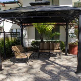 A peaceful outdoor seating area under a gazebo with benches and surrounding plants.