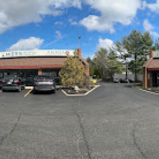 A panoramic view of a commercial building with a parking lot under a partly cloudy sky.