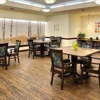 A spacious dining room with multiple tables and chairs, featuring wooden flooring and modern lighting.