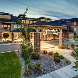 The exterior of a well-lit hotel entrance with landscaped surroundings.