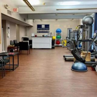 A well-equipped gym with various exercise machines and colorful medicine balls.
