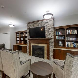 A cozy living room featuring a stone fireplace, built-in bookshelves, and comfortable seating around a central table.