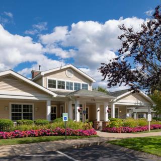 A suburban building surrounded by a well-maintained garden under a partly cloudy sky.