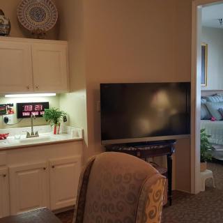 A cozy living room with a TV and a kitchenette.