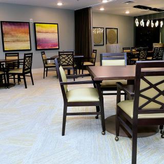 A modern dining area with tables, chairs, and colorful artwork on the walls.