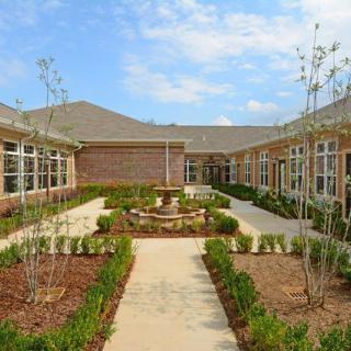A beautifully landscaped courtyard with a central pathway and a fountain, surrounded by buildings.
