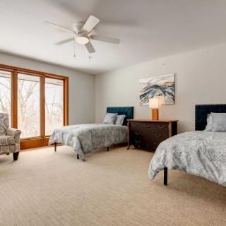 A modern bedroom with two twin beds, a large window, and stylish decor.
