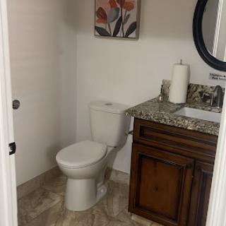 A well-appointed bathroom featuring a modern toilet, elegant vanity with granite countertop, and decorative artwork.