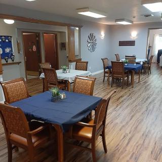 A clean and organized dining area with wooden floors and blue tablecloths.