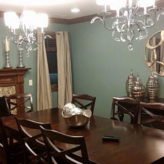 A well-decorated dining room featuring a large table, elegant chandeliers, and a stylish fireplace mantel.