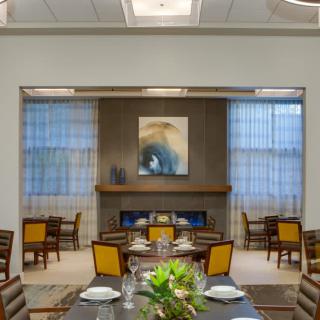 A modern dining room with elegant decor, featuring a central fireplace and contemporary artwork.